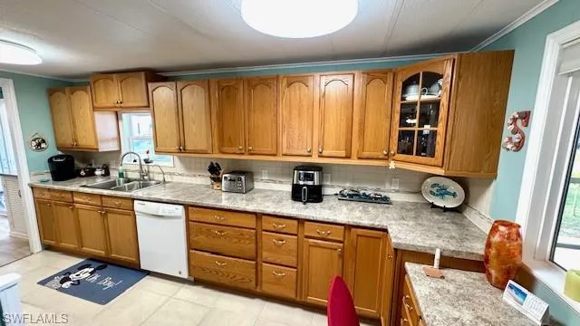Kitchen featuring decorative backsplash, white dishwasher, a healthy amount of sunlight, and sink