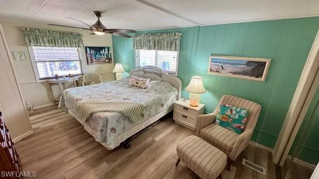 Large Bedroom featuring multiple windows, ceiling fan, wood-style flooring
