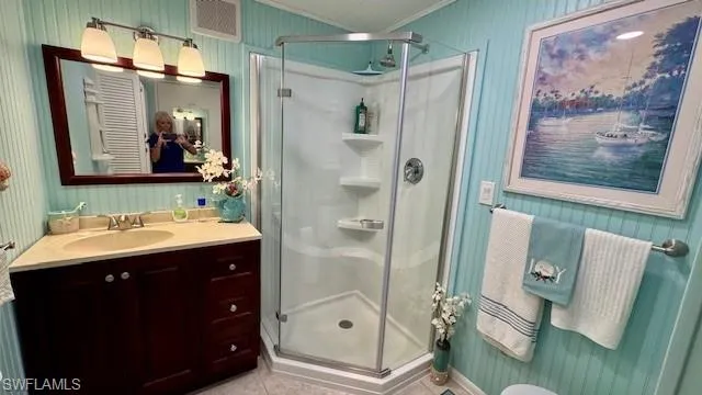 Bathroom featuring tile patterned flooring, vanity, a shower with door, and crown molding