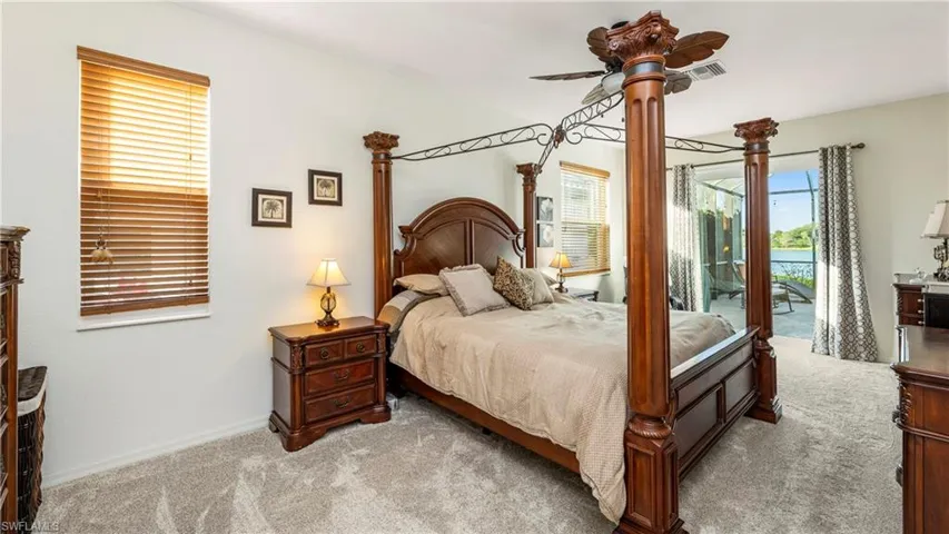 Downstairs Master Bedroom with a ceiling fan, access to exterior, light carpet, and a water view