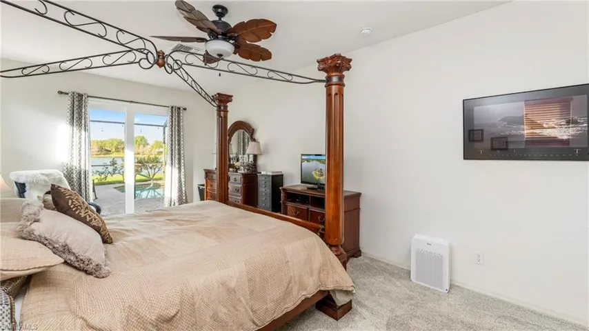Downstairs Master Bedroom with light colored carpet, access to outside, and a ceiling fan