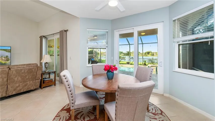Dining room featuring light tile patterned floors, a sunroom, a water view, and ceiling fan