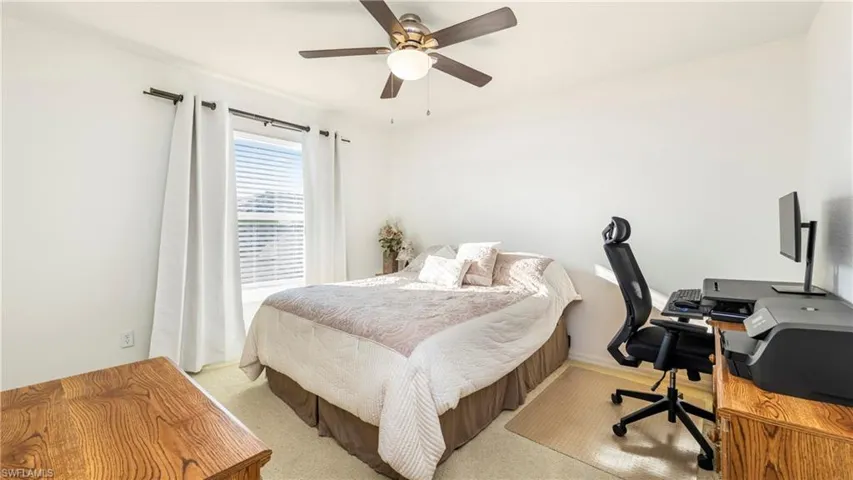 Bedroom with an office area, light carpet, and ceiling fan
