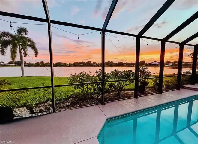 Pool at dusk with screen enclosure, an outdoor pool, and a sunroom