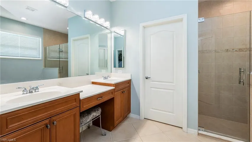 Master bath en-suite featuring double vanity, a shower stall, and light tile patterned flooring
