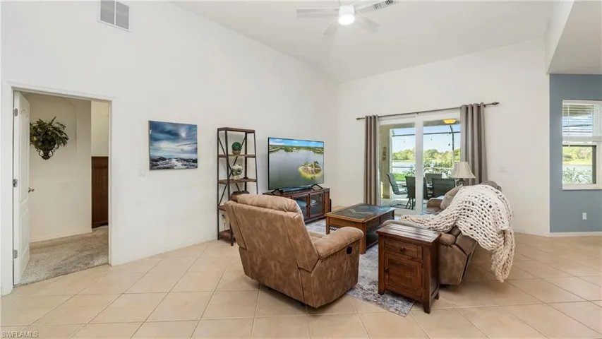 Living area with ceiling fan, vaulted ceiling, and light tile patterned flooring
