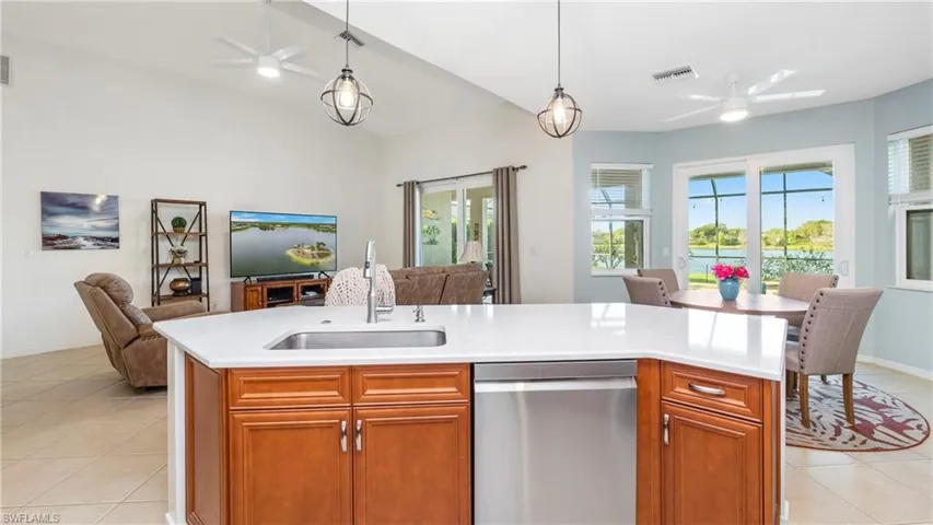 Kitchen featuring a ceiling fan, open floor plan, light tile patterned floors, stainless steel dishwasher, and vaulted ceiling