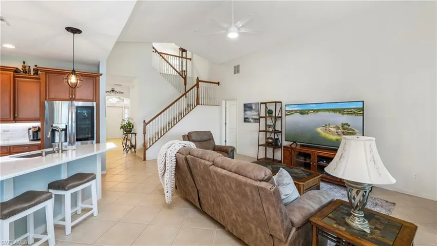 Living area with light tile patterned floors, a ceiling fan, and lofted ceiling