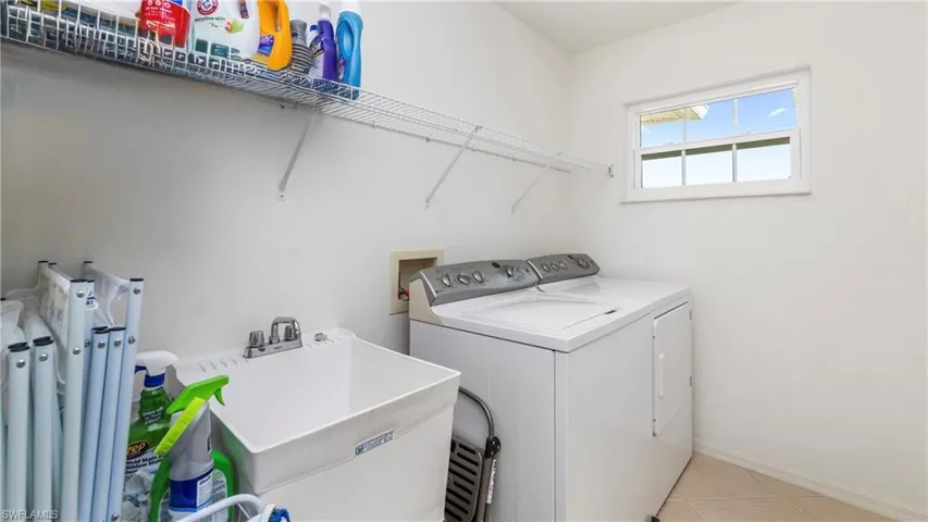 Laundry area with independent washer and dryer and light tile patterned floors