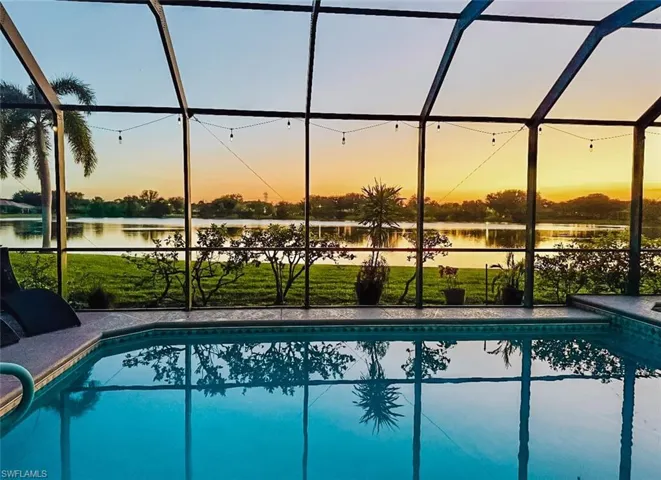 Outdoor pool featuring screen enclosure, a sunroom, and a lawn
