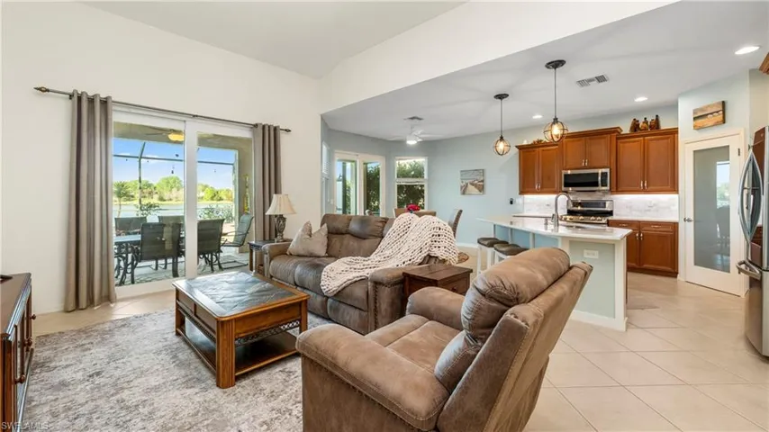 Living room with plenty of natural light, light tile patterned floors, and ceiling fan
