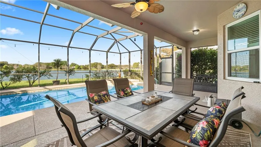 View of patio / terrace with an outdoor pool, a sunroom, outdoor dining area, screen enclosure, and a water view