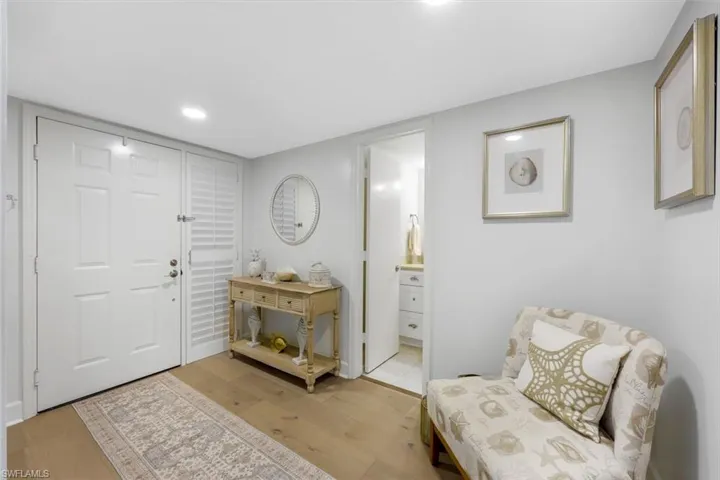 Recessed ceiling lighting, durable wood-finish flooring, and a paneled entry door with an adjacent louvered closet