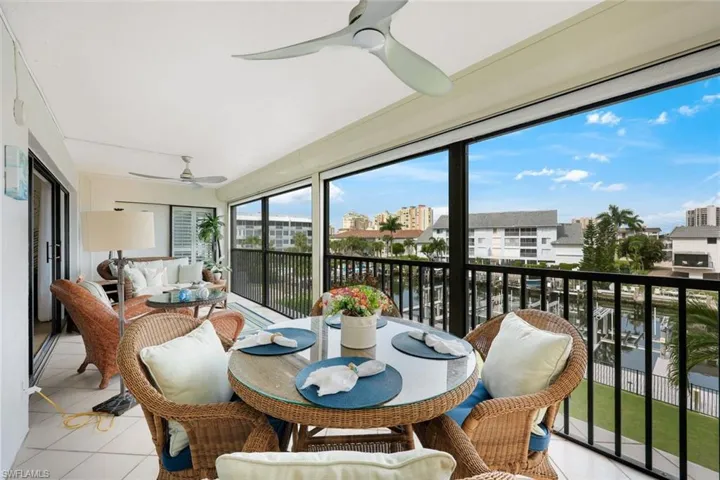 Enclosed balcony with tiled flooring, multiple ceiling fans, and a waterfront backdrop