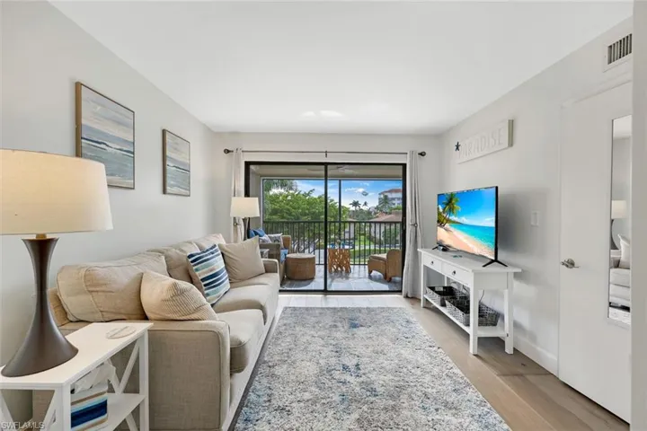 Light-toned wood-finish flooring, sliding glass door to exterior balcony, and a white interior door with brushed nickel hardware