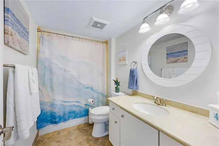 White vanity with an integrated sink and light-toned countertop, paired with a large round mirror