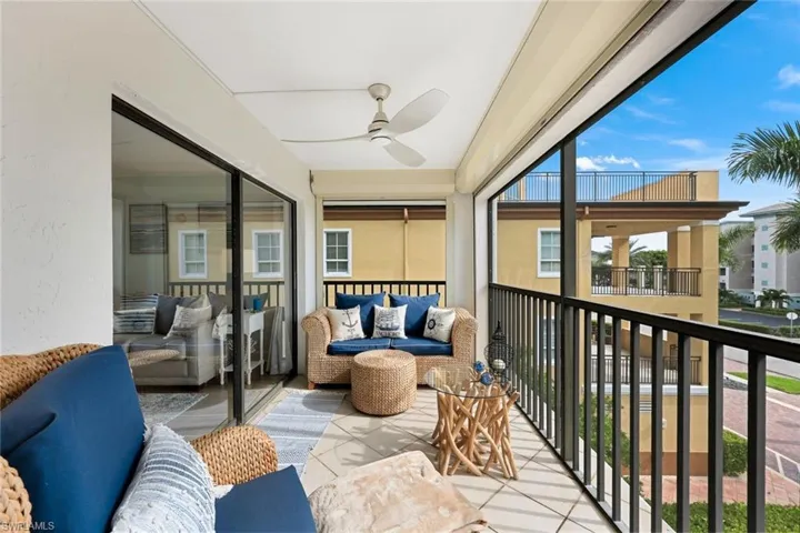 Balcony featuring tile flooring, a ceiling fan, black metal railings, and a large sliding glass door