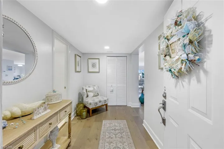 Wood-finish flooring extending from the entry, a closet with bi-fold louvered doors, and recessed lighting