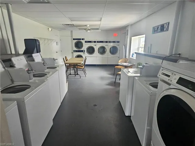 Community laundry with a paneled ceiling, ceiling fan, and washing machine and clothes dryer