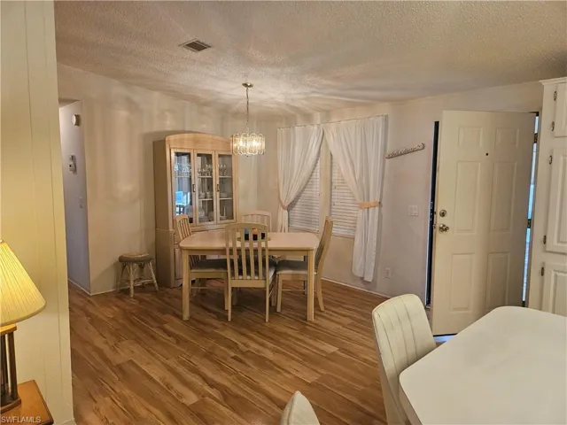 Dining room featuring wood finished floors, a textured ceiling, and a chandelier