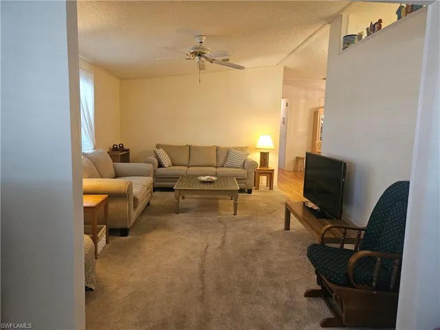 Carpeted living room featuring a textured ceiling and a ceiling fan