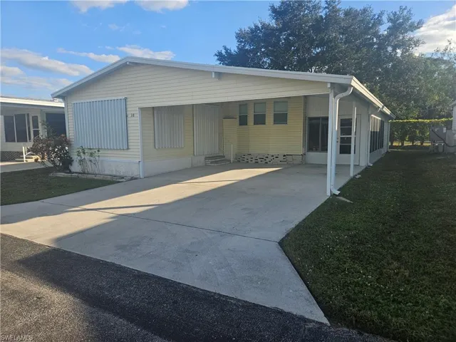 Manufactured / mobile home featuring an attached carport, driveway, and a front lawn