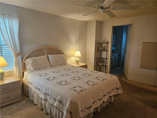 Carpeted bedroom with ensuite bath, a textured ceiling, and a ceiling fan