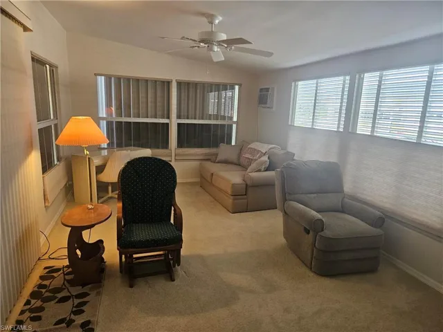 Carpeted living room featuring ceiling fan, lofted ceiling, and a wall unit AC