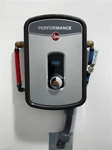 Wall-mounted Rheem Performance water heater unit featuring a digital display, control dial, and visible plumbing connections