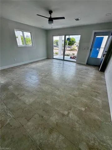 Spacious room featuring large format tile flooring, a modern ceiling fan, recessed lighting, and a sliding glass door providing exterior access