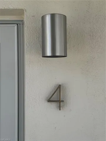 Modern brushed metal cylindrical outdoor light fixture mounted on textured exterior wall