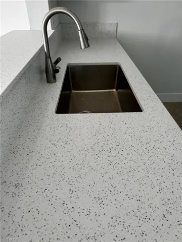 White speckled countertop with an undermount stainless steel sink and a gooseneck faucet