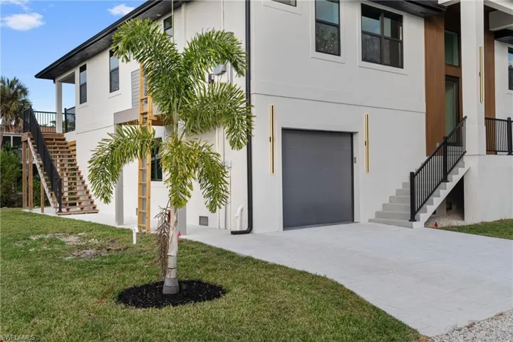 View of front of property featuring stairway, a garage, stucco siding, and a front yard