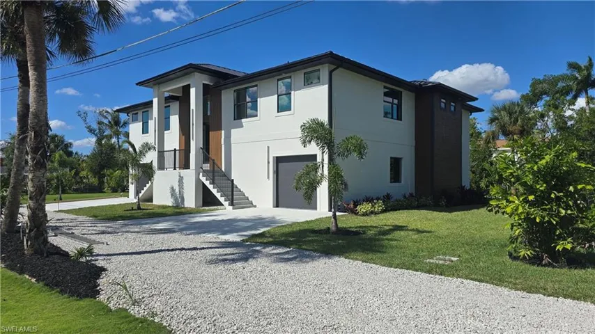 Contemporary home featuring gravel driveway, a front yard, stucco siding, and a garage