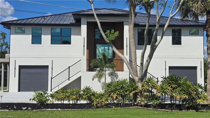 View of front of home with stucco siding, an attached garage, a metal roof, and a standing seam roof