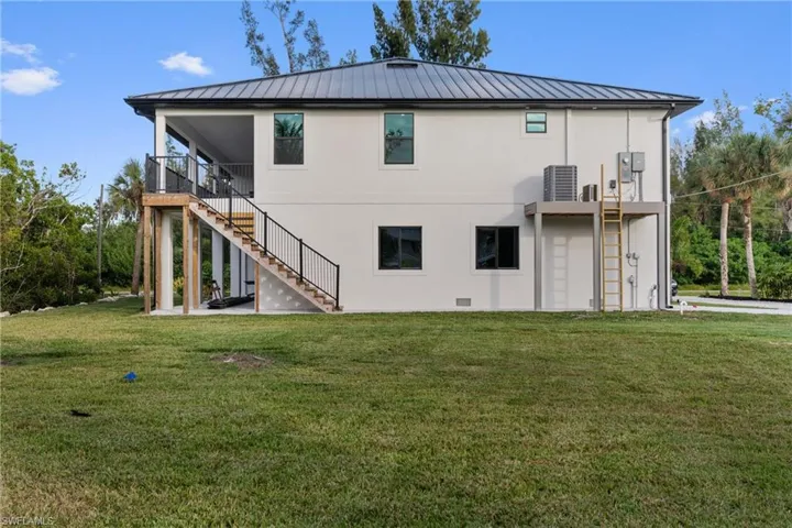 Back of property featuring a yard, stairway, a patio, and a standing seam roof