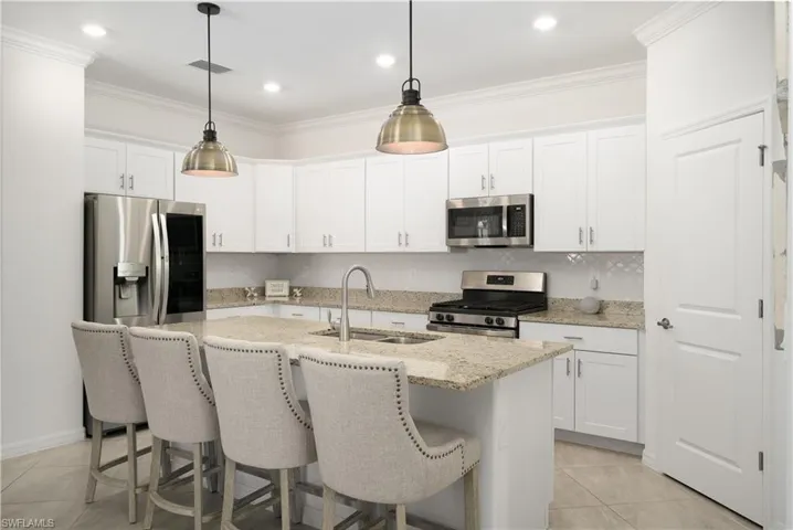 White Shaker Style Cabinetry with center island and gorgeous white arabesque pattern tile backsplash and corner walk in pantry