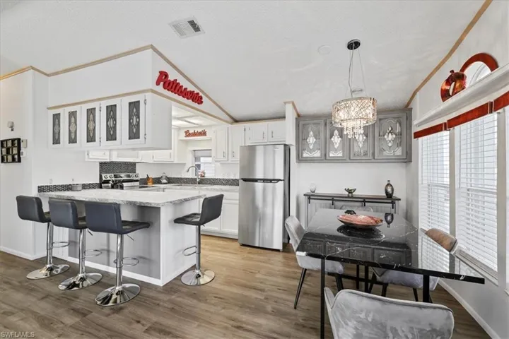 Kitchen with glass insert cabinets, wood finished floors, a breakfast bar area, a textured ceiling, and appliances with stainless steel finishes
