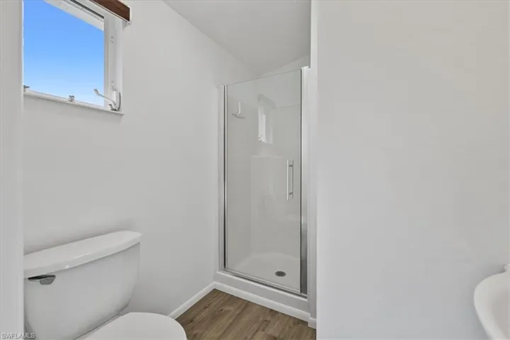 Full bath with wood finished floors and a stall shower
