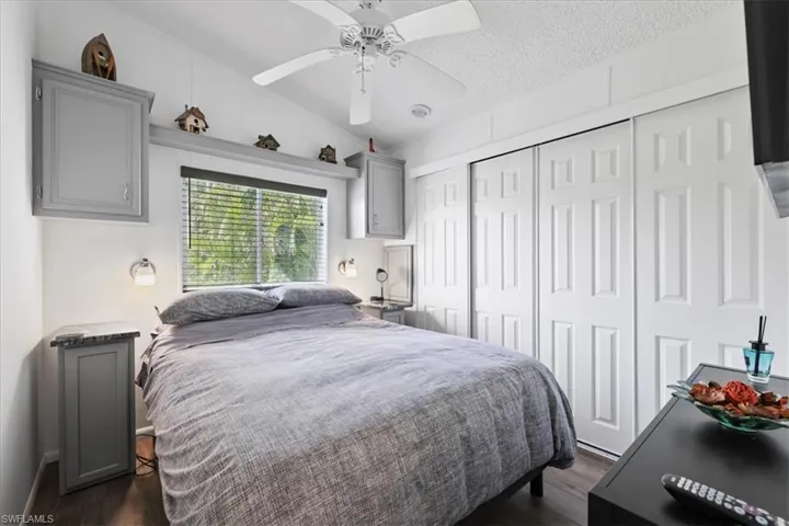 Bedroom with dark wood finished floors, ornamental molding, lofted ceiling, a ceiling fan, and a closet
