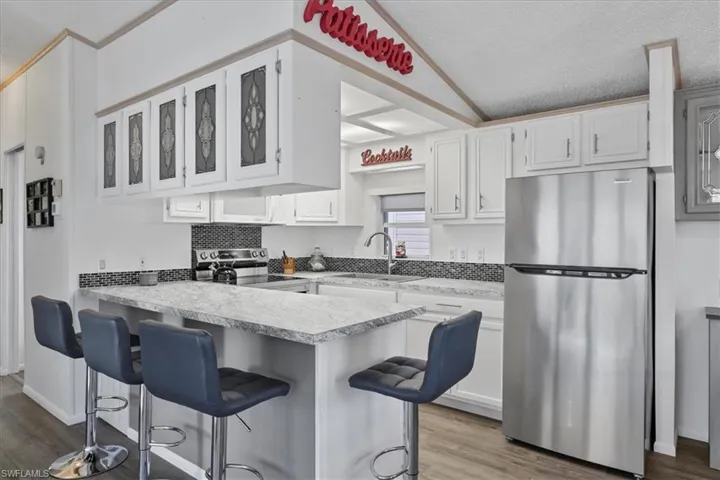 Kitchen with stainless steel appliances, white cabinets, dark wood finished floors, light countertops, and a textured ceiling