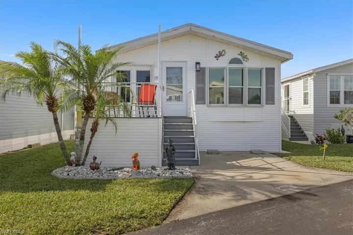 Manufactured / mobile home with stairs, a front lawn, and a balcony