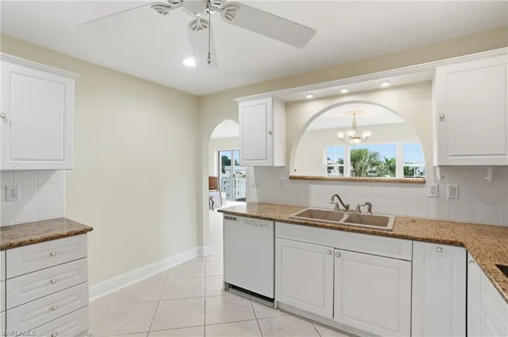 Kitchen featuring decorative backsplash, white cabinetry, a ceiling fan, and white dishwasher