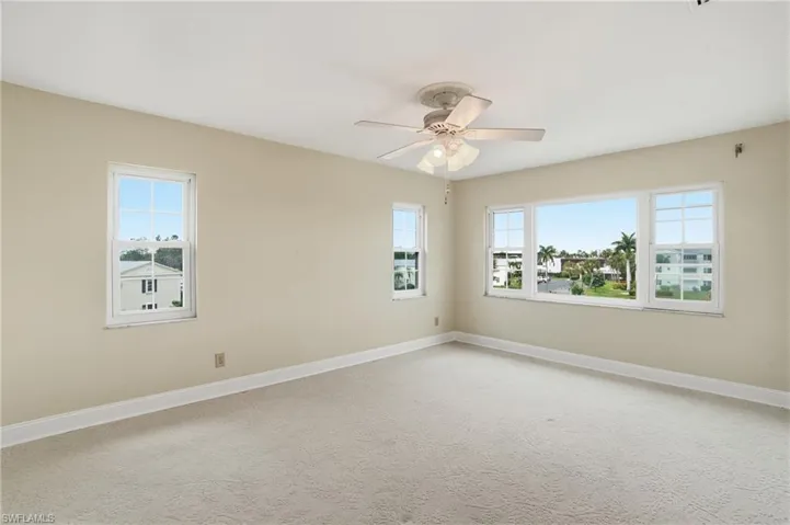 Empty room with light carpet and a ceiling fan
