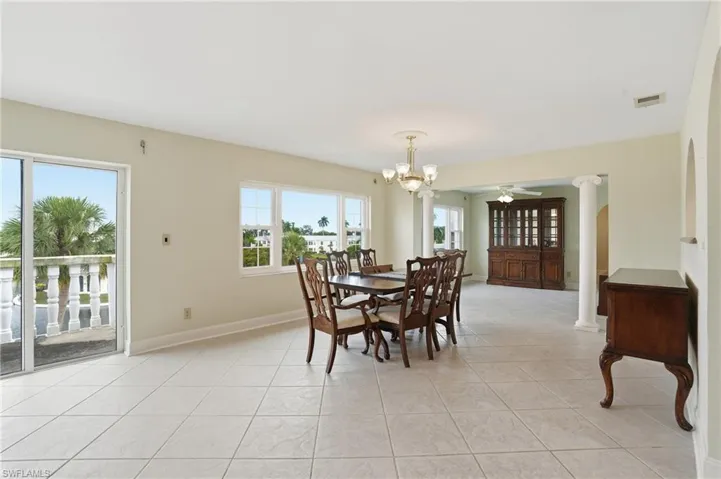 Dining space with suspended lighting, ceiling fan, decorative columns, and light tile patterned floors