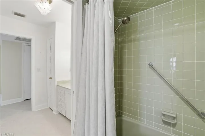 Bathroom with shower / bathtub combination with curtain, a closet, vanity, and light tile patterned floors