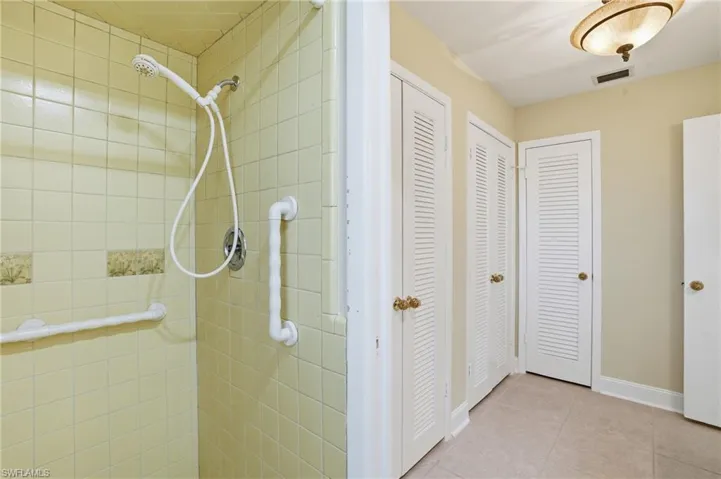 Full bathroom with a closet, tiled shower, and light tile patterned flooring