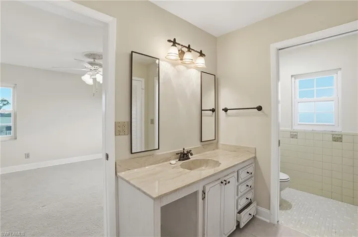 Bathroom featuring vanity, a ceiling fan, and light carpet