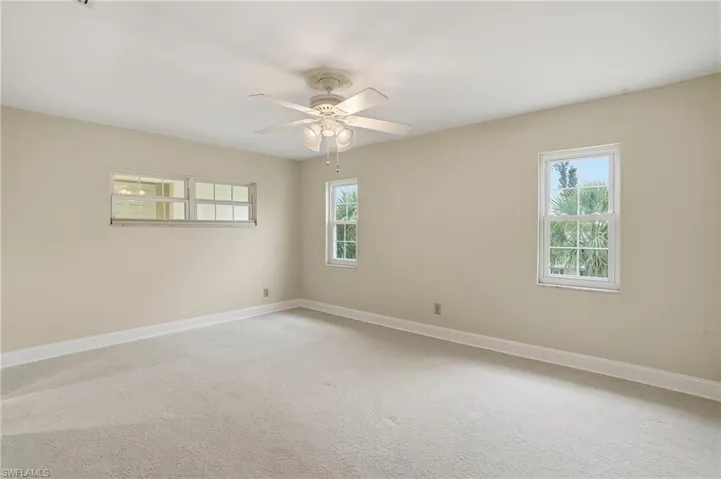 Spare room featuring light carpet, healthy amount of natural light, and ceiling fan