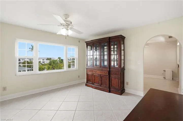 Unfurnished room featuring arched walkways, ceiling fan, and light tile patterned floors